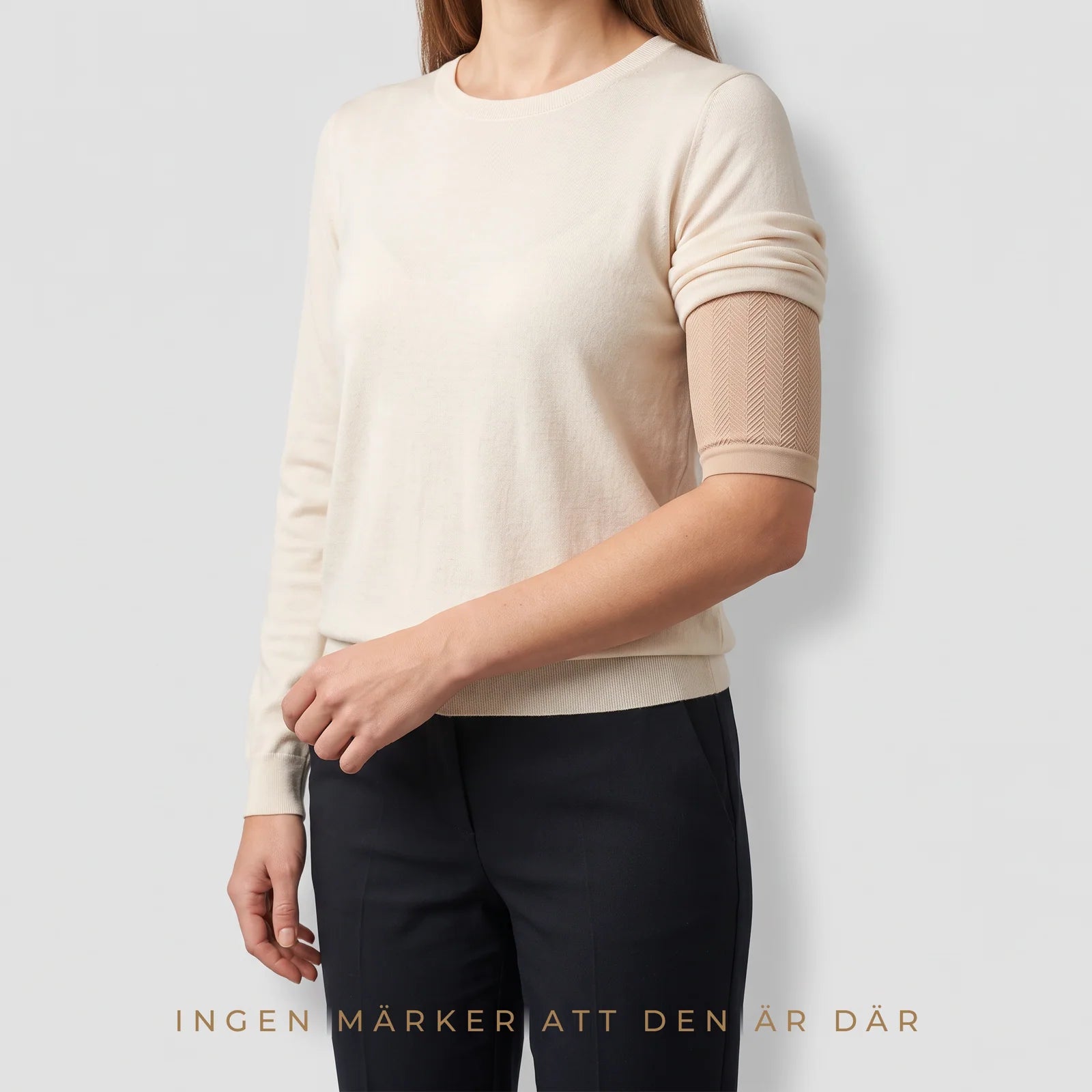 Beige Sculpt™ kompressionsärm som bärs diskret under en krämvit tröja