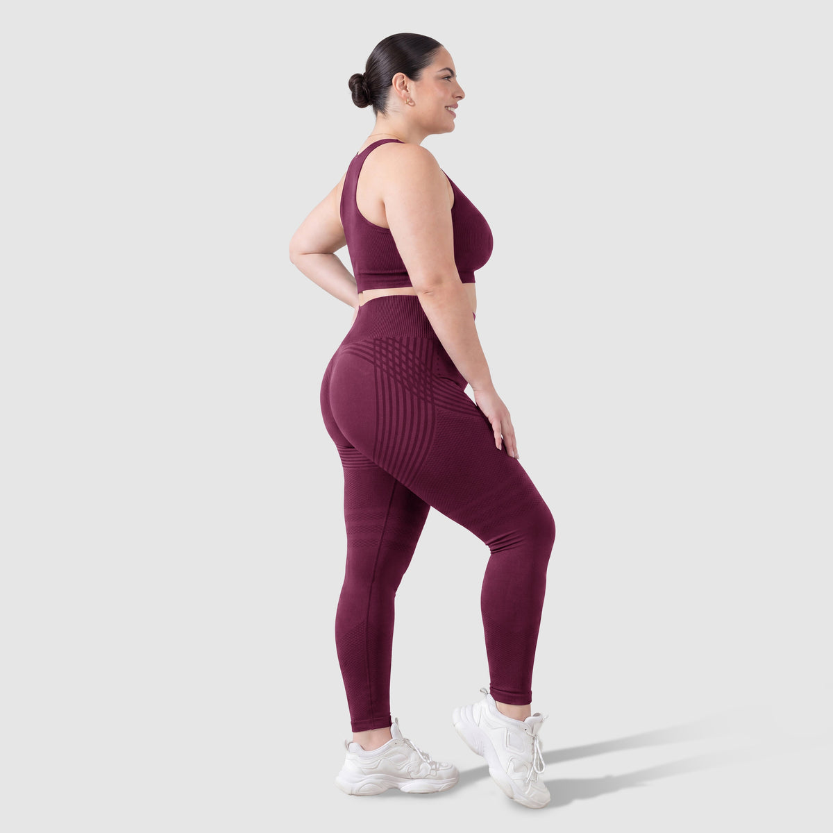 Kvinna i Sculpt 3D™ anticellulitleggings i plommon, från sidan, med de formande 3D-linjerna synliga