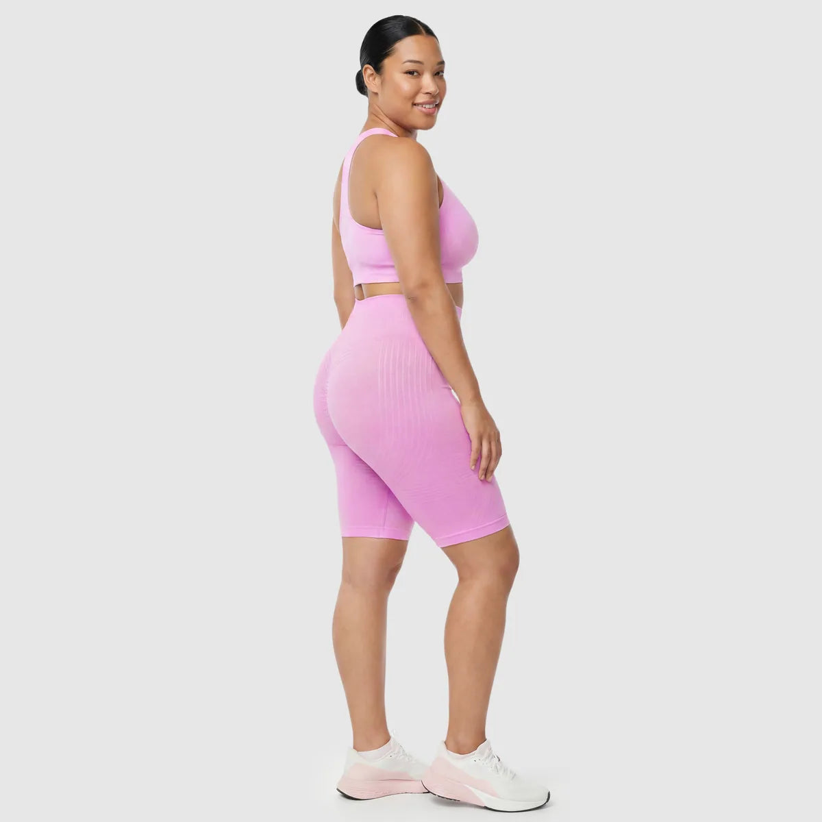 Kvinna i Sculpt 3D™ anticellulitshorts i rosa, från sidan, med de formande 3D-linjerna synliga
