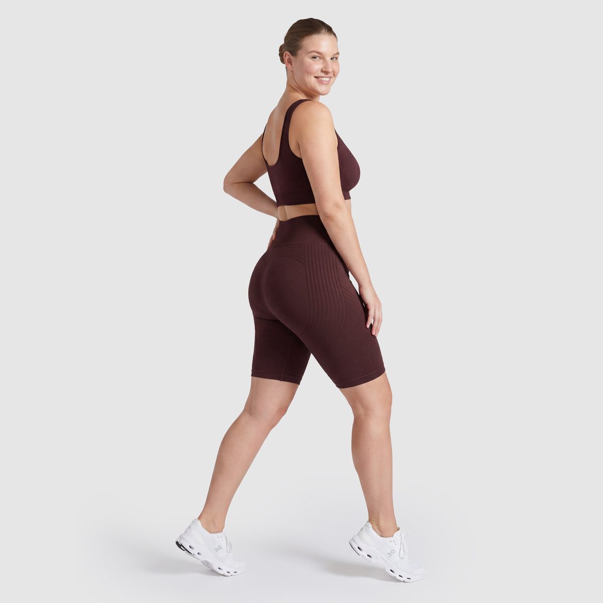 Kvinna i Sculpt 3D™ anticellulitshorts i plommon, från sidan, med de formande 3D-linjerna synliga