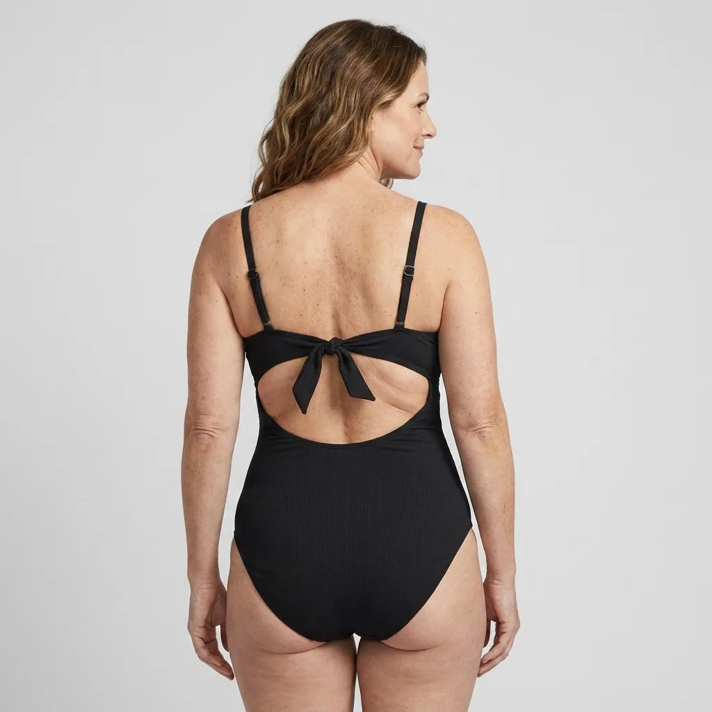 Kvinna i Sculpt™ baddräkt med vriden front och cutouts i svart, bakifrån med knytdetalj i ryggen